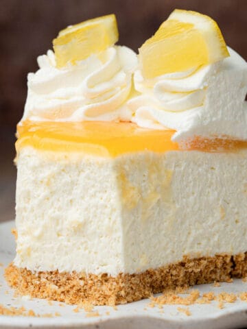 A slice of lemon curd cheesecake on a plate with a bite taken out.