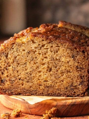 Cardamom banana bread on a wooden serving plate.