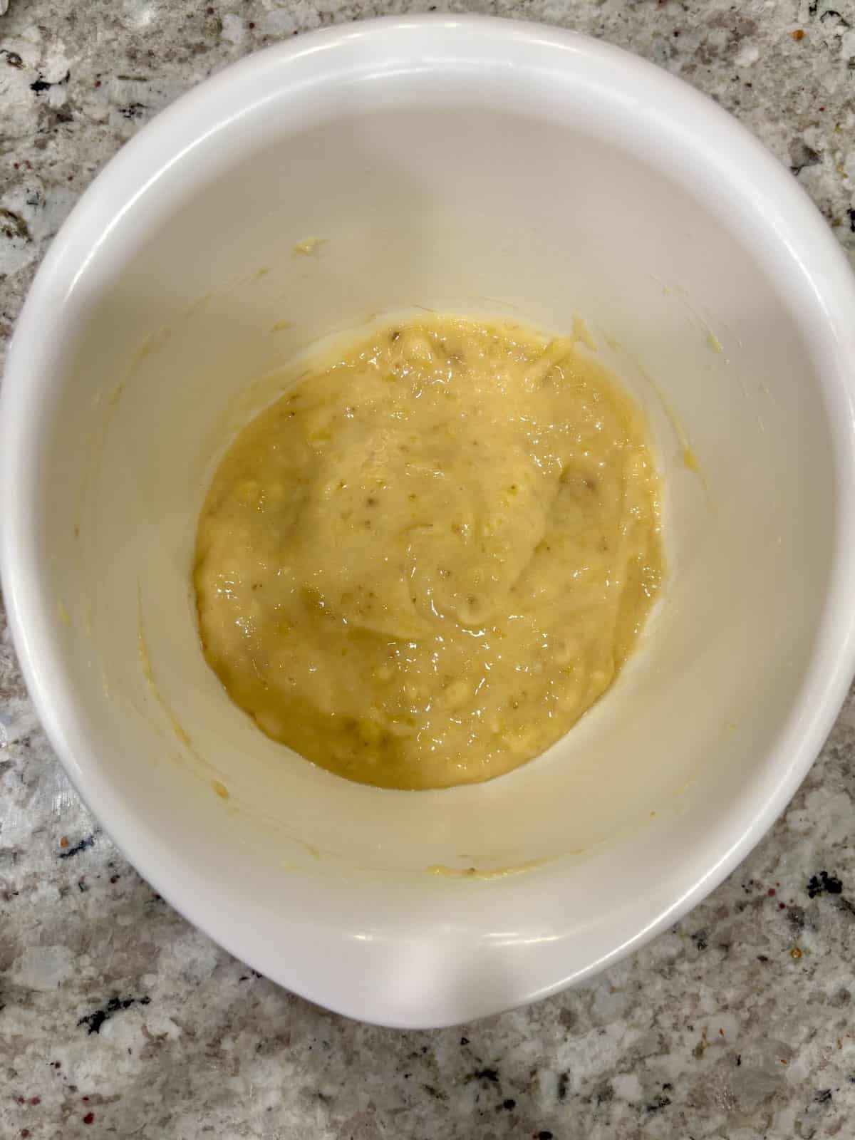 Mashed banana in a white bowl on the counter.