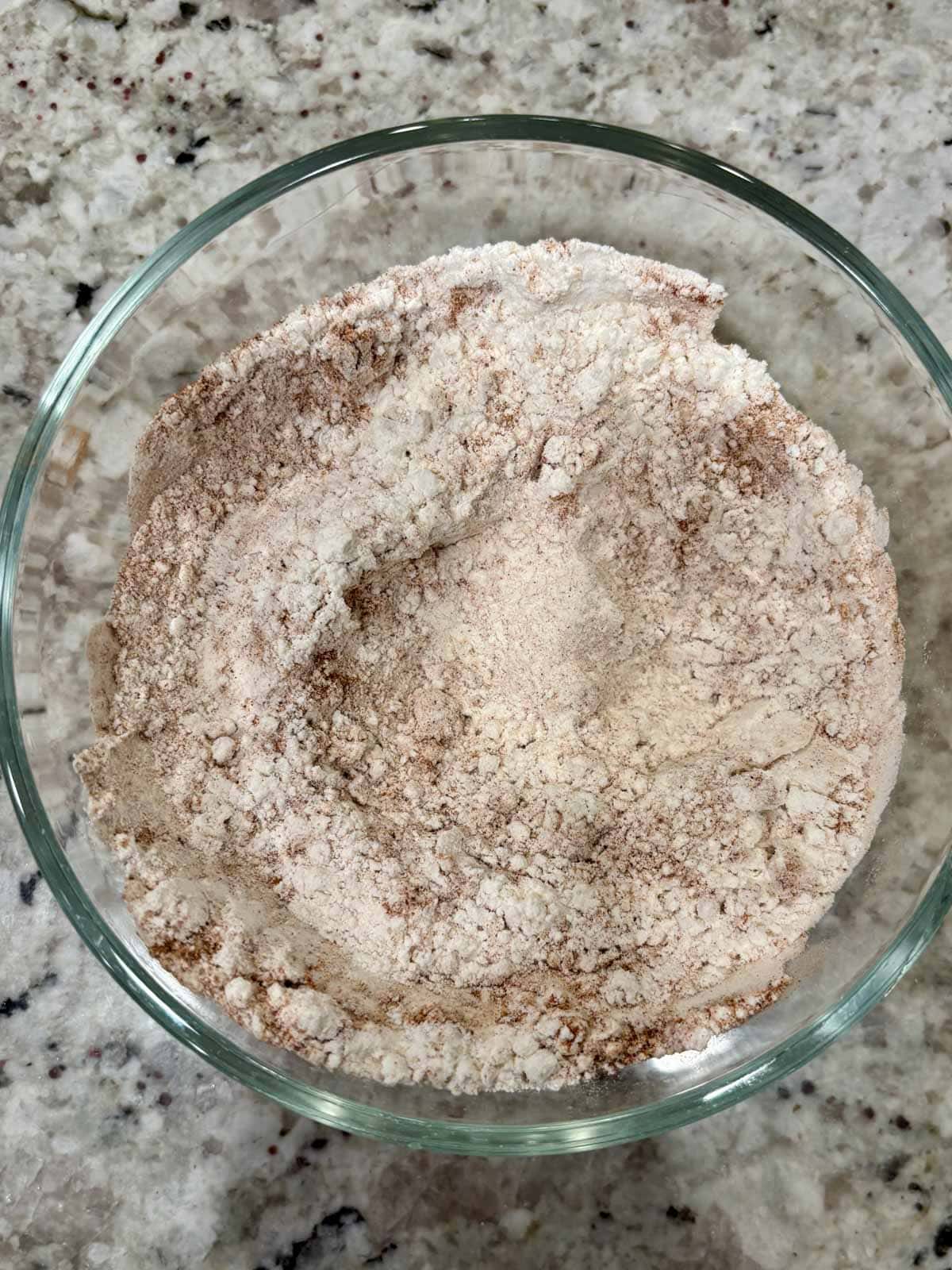 Dry ingredients for the banana bread in a glass bowl on the counter.