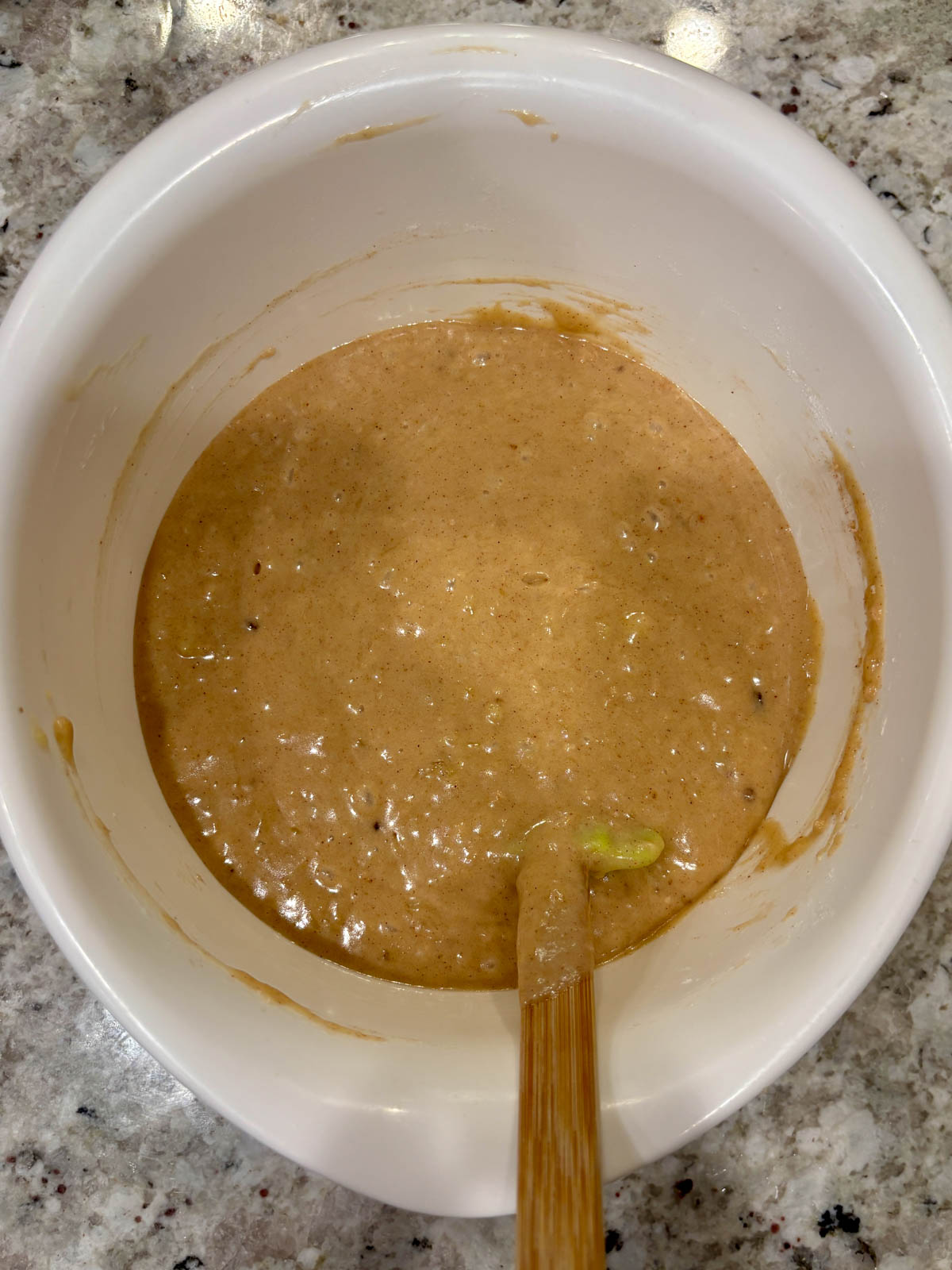 Banana bread batter in a white bowl with a spatula.