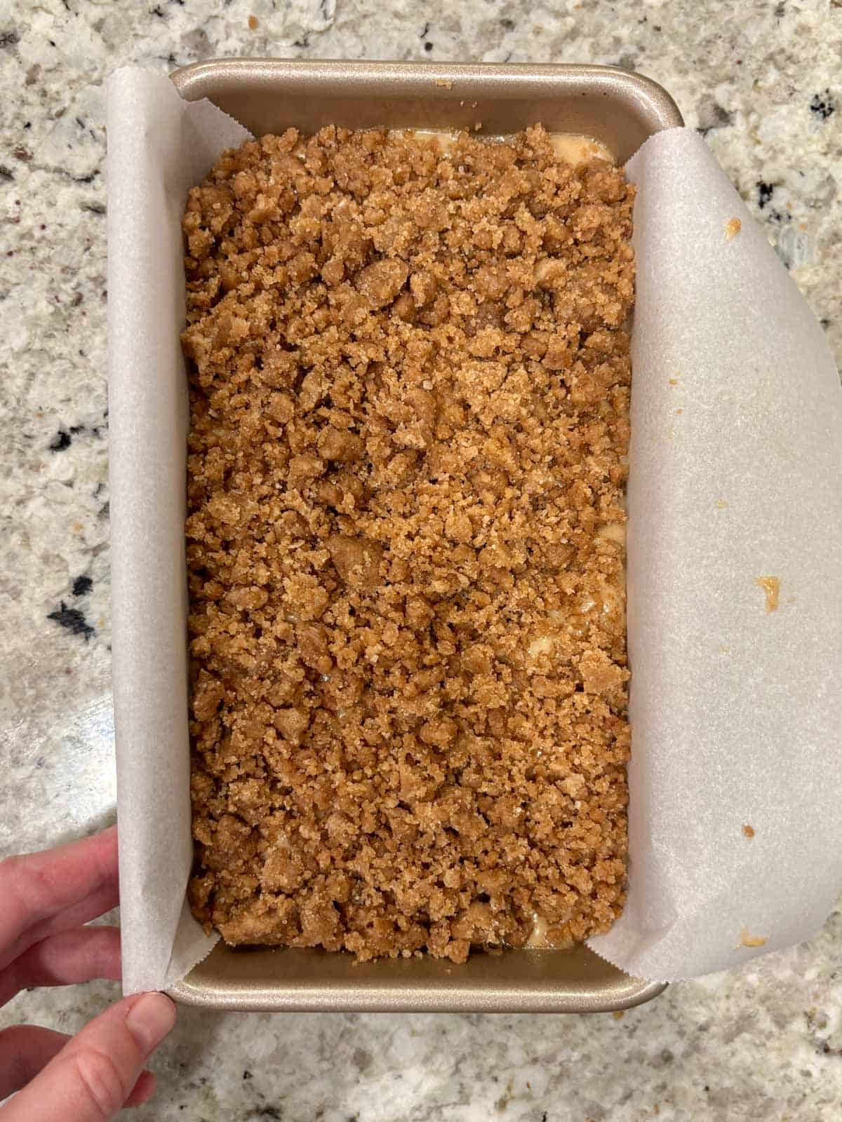 Streusel topping on top of the banana bread batter in a pan.