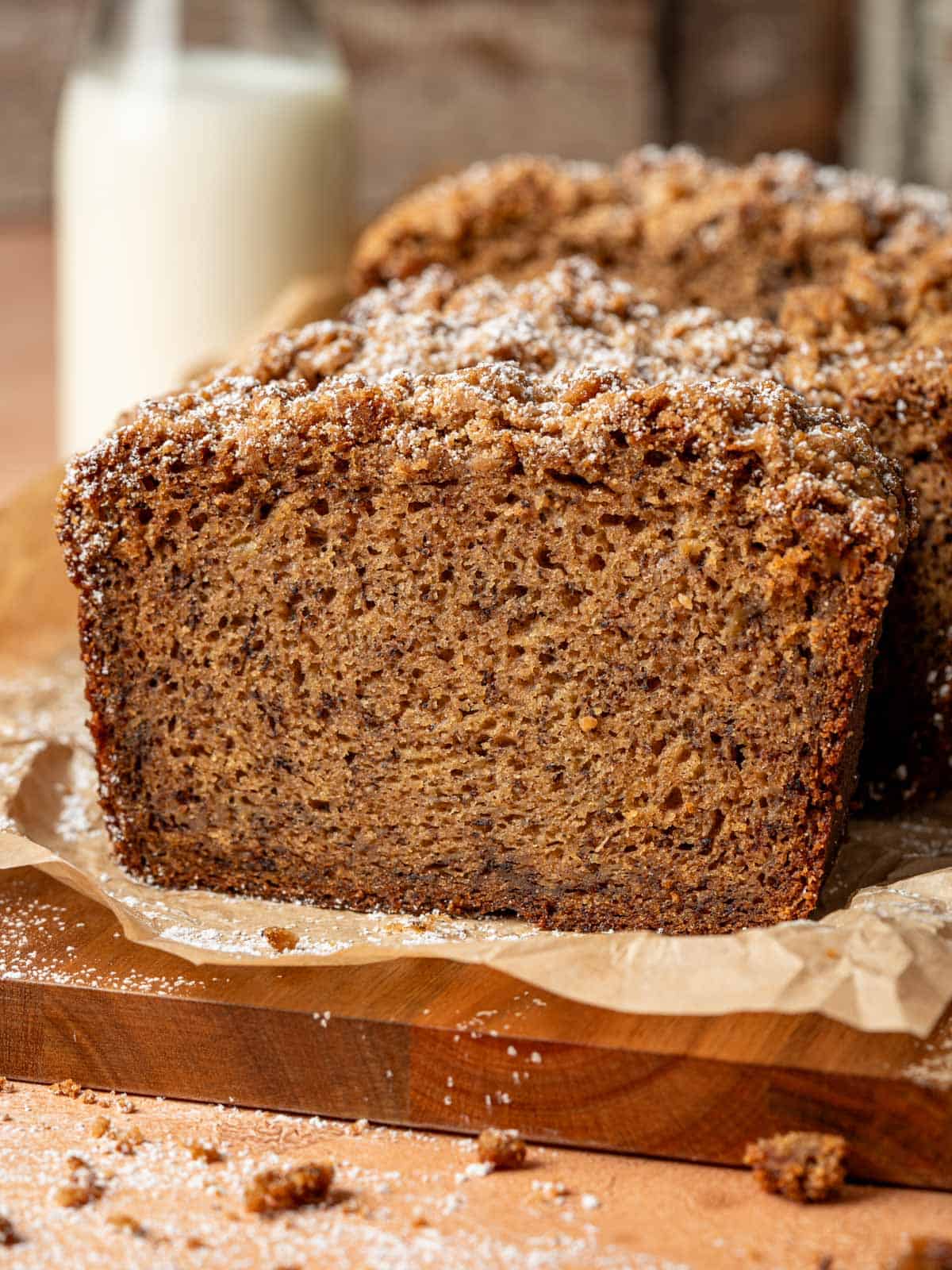 Moist banana bread slice on a cutting board with streusel topping.