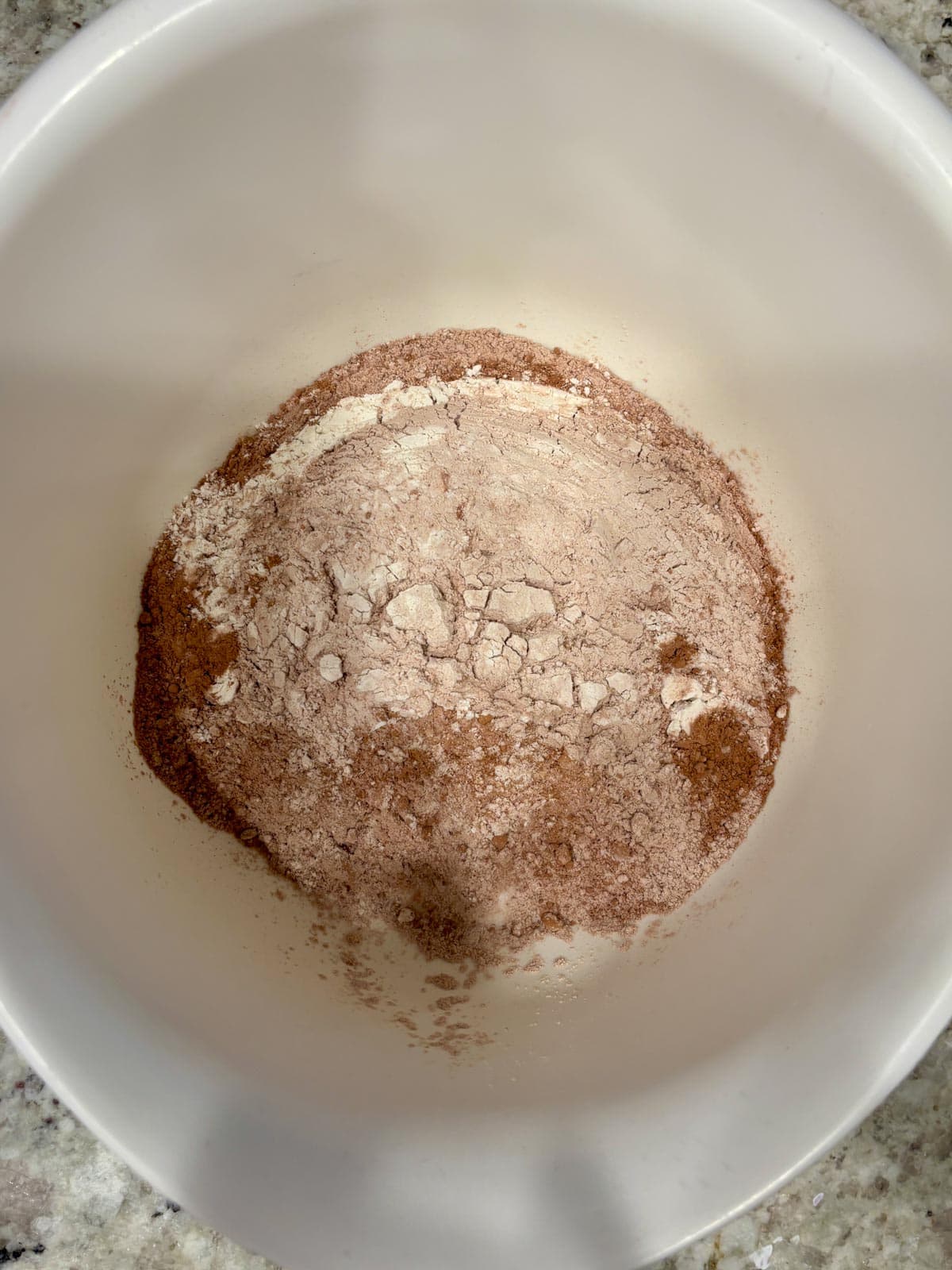 Dry ingredients fro the chocolate cake in a white bowl on the counter.