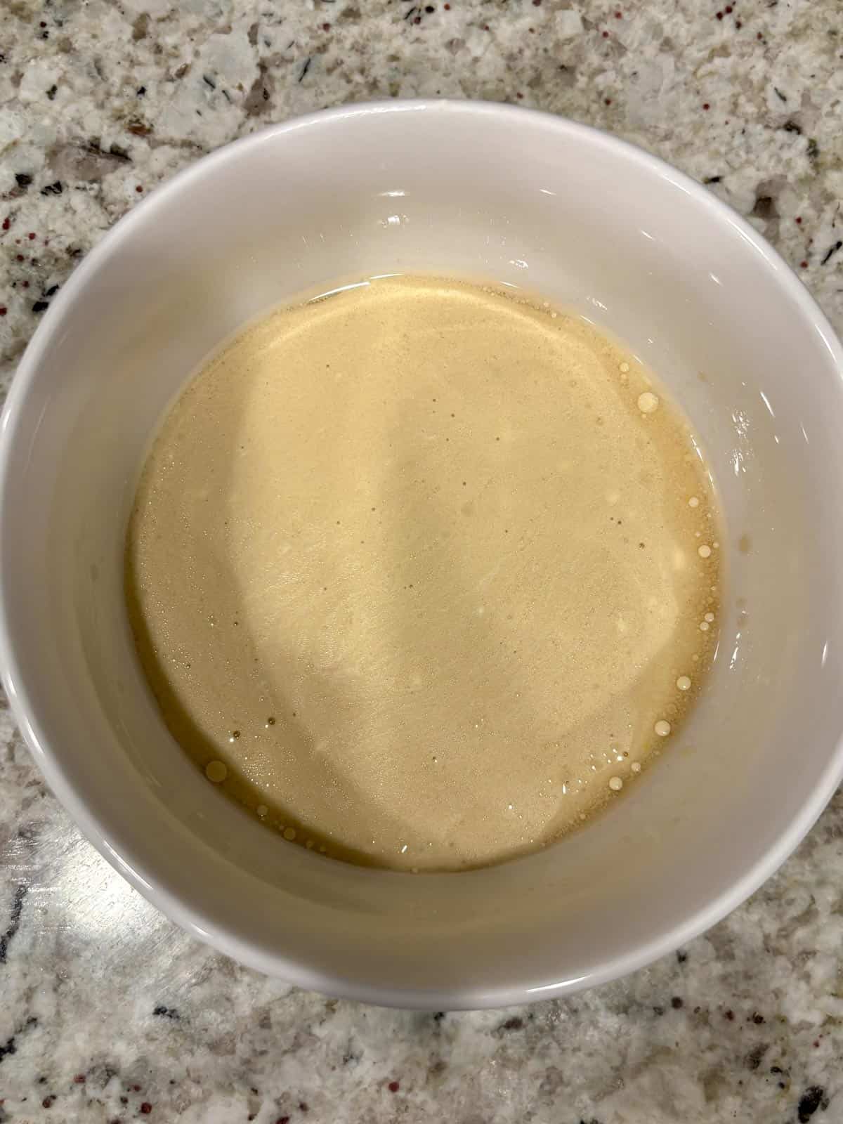 The wet ingredients for the chocolate cake in a white bowl on the counter.