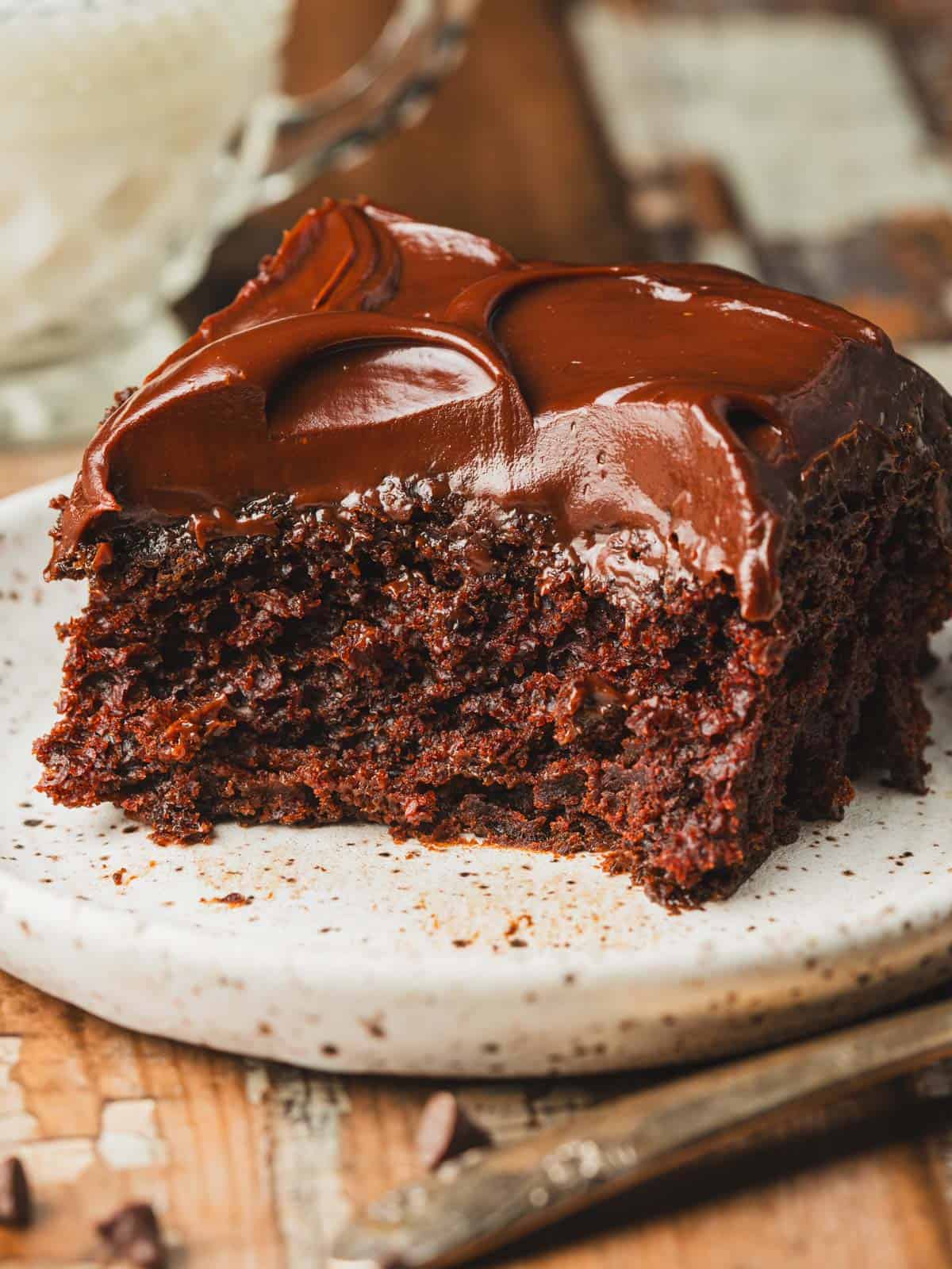 Chocolate ganache cake on a plate with milk in the background.