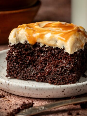 Chocolate salted caramel cake on a white plate with milk in the background.