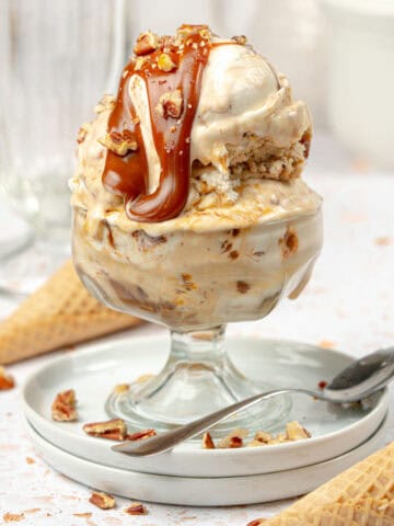 Turtle ice cream in a bowl with caramel, chocolate, and pecans on top.
