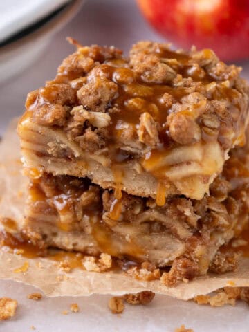 A stack of apple bars with salted caramel on top and oats around.