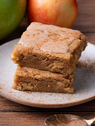 Apple blondies with cinnamon and apples on a plate stacked.