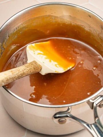 A saucepan with salted caramel sauce in it with a spatula.