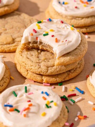 Soft sugar cookies stacked on top of each other with frosting and sprinkles.