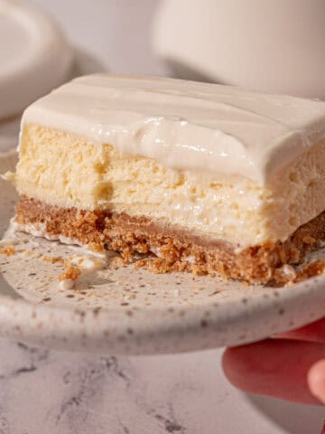 A plate with easy vanilla cheesecake bars on it with a bite taken out.
